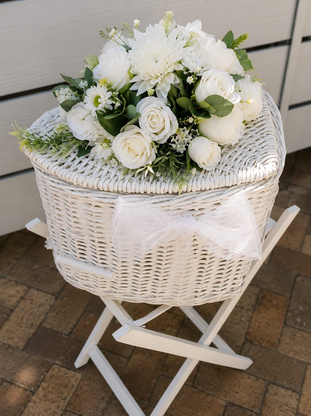 A heart-shaped white wicker basket topped with white roses and an organza bow