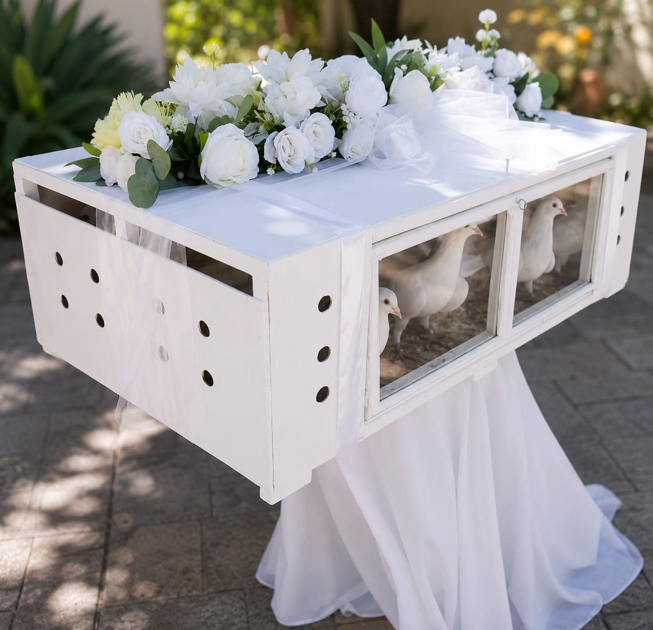 A white release box of doves with white roses and eucalyptus on a draped stand